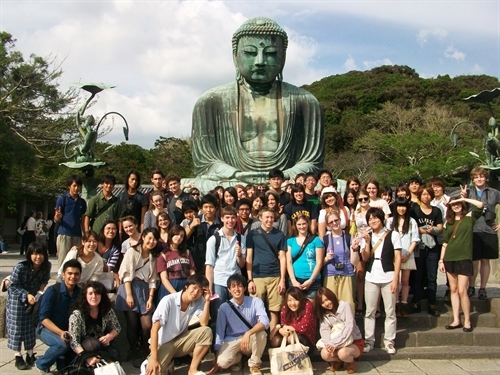 large group of students in front of a buddha statue in Japan